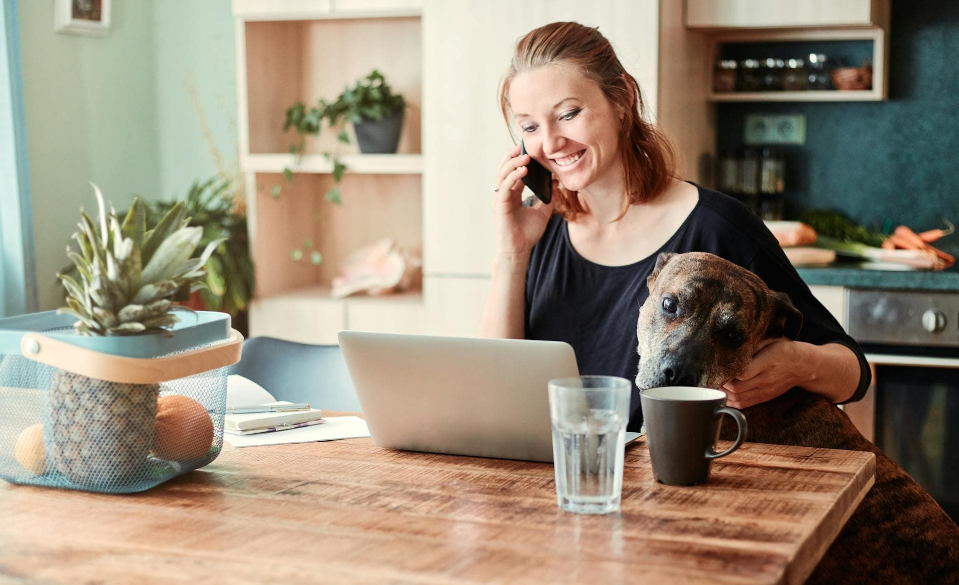 A solo dog trainer working on session notes at their laptop with her dog
