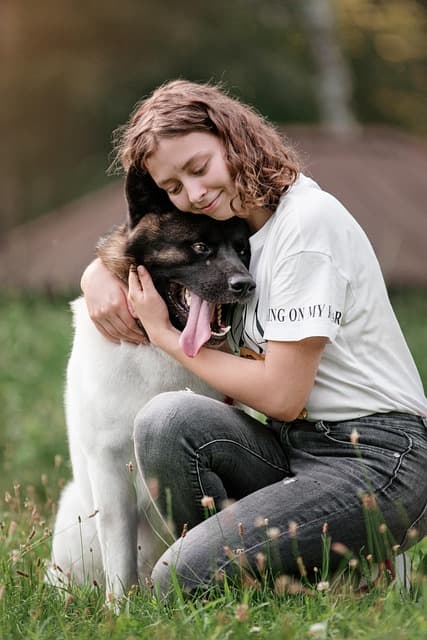 A happy dog trainer hugs her dog.